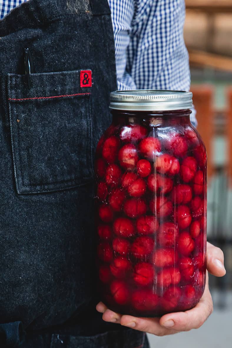 Holding a jar of pickled cherries