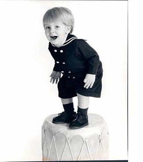 Kobi as a baby standing on a drum