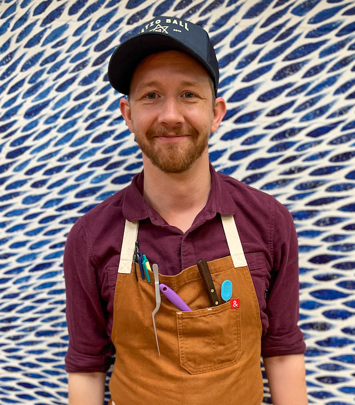 Our Sous Chef wearing a Matzo Ball Mafia hat and a chef apron holding many chef tools